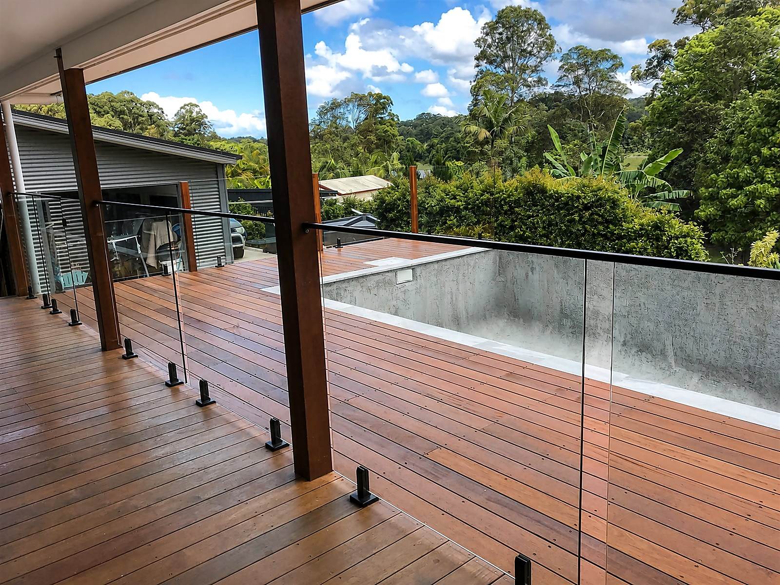 Hardwood deck and glass balustrade overlooking a green landscape.