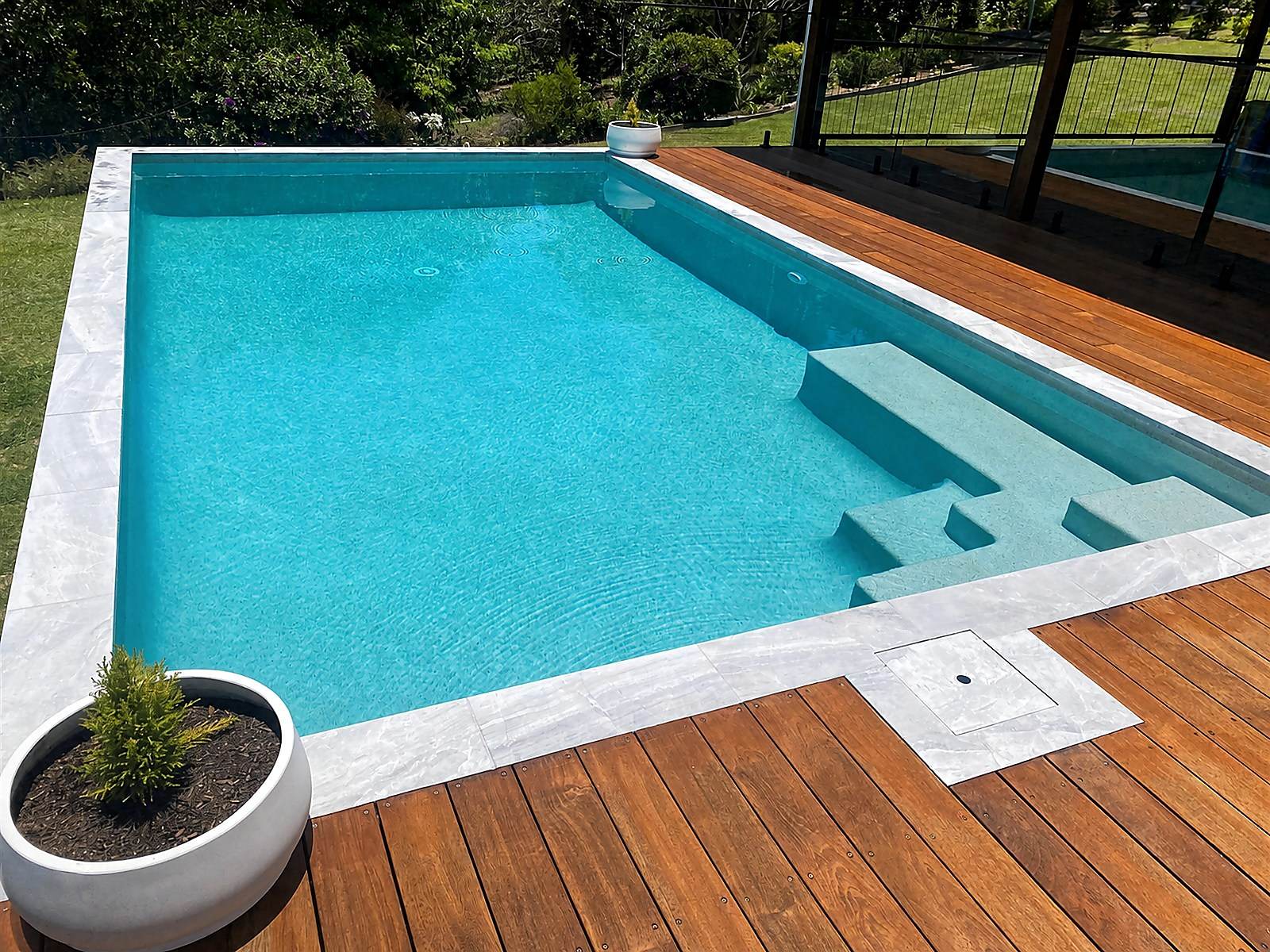 Swimming pool edged by a finished hardwood deck.